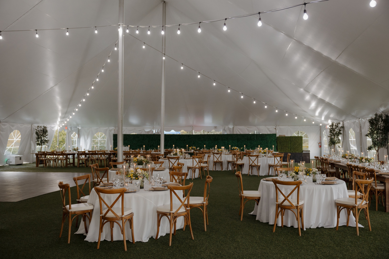 Outdoor event setup with string lights and farmhouse tables
